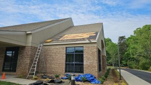 A sturdy house with a well-maintained roof stands protected against a backdrop of dark storm clouds and hail stones.